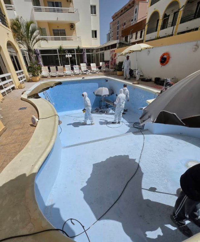 Trabalhadores a aplicar revestimento no interior de uma piscina