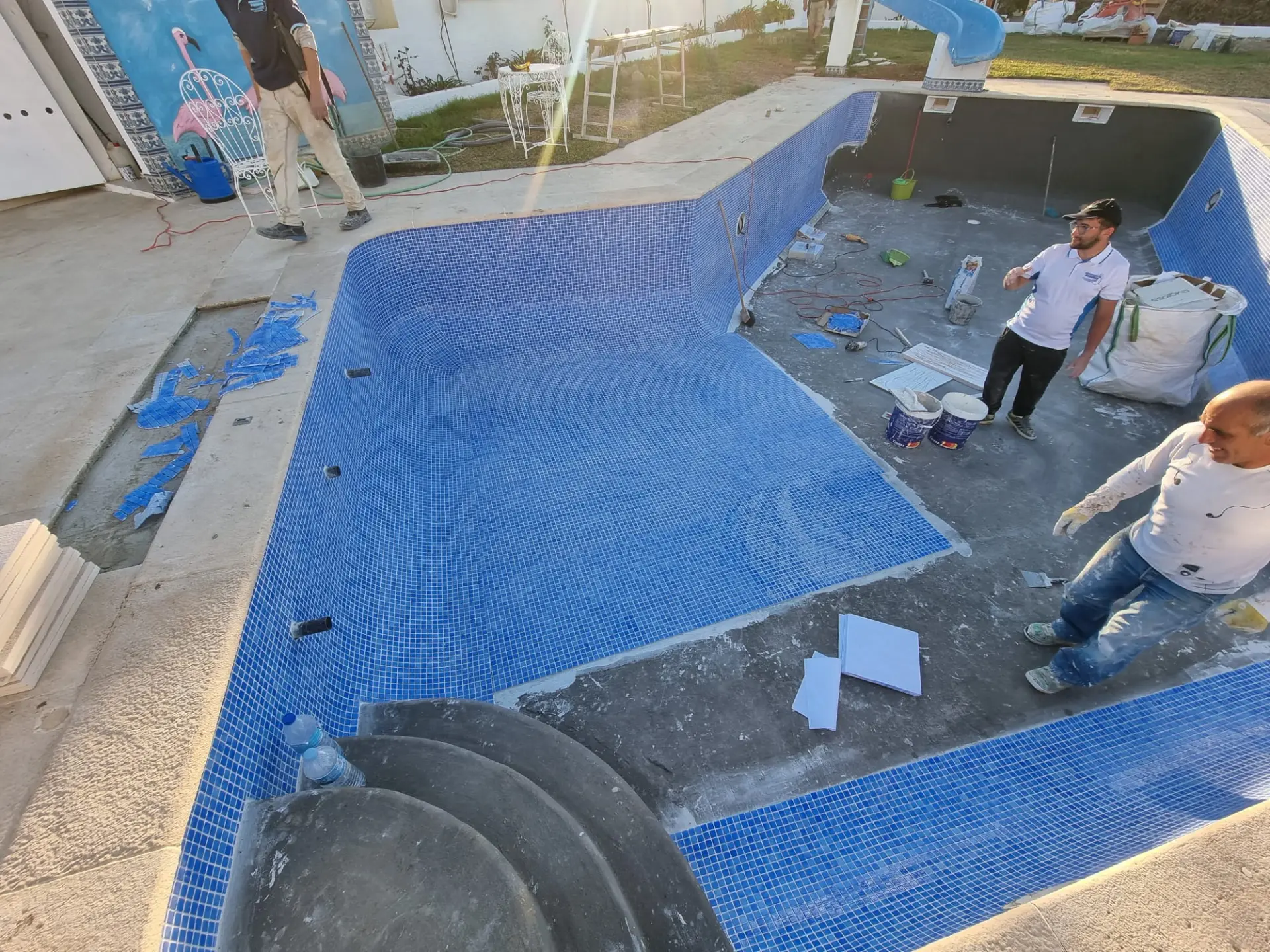Equipa a aplicar novo mosaico no interior de uma piscina